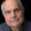 Headshot of Mike McShane on a dark background